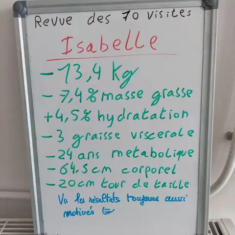 Dans la salle, une membre pose avec son bilan noté sur une ardoise blanche