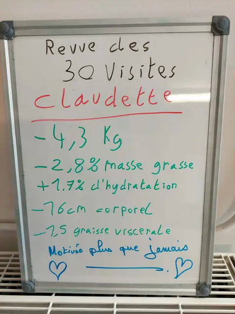 Dans la salle, une membre pose avec son bilan noté sur une ardoise blanche