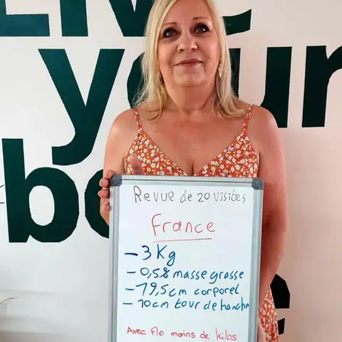 Dans la salle, une membre pose avec son bilan noté sur une ardoise blanche